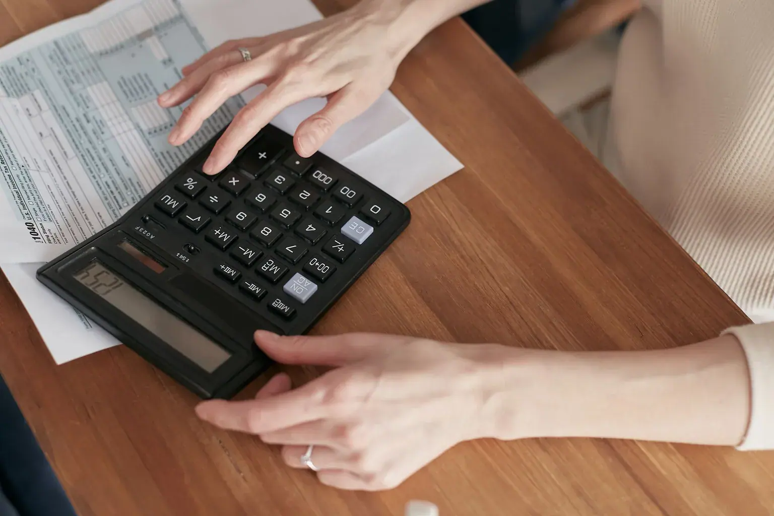 Hands reviewing bills with a calculator